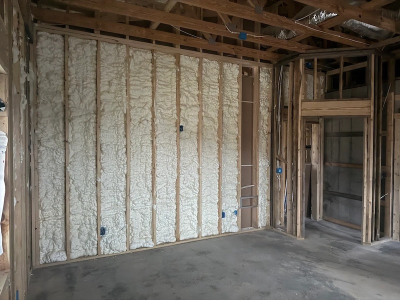 builder applying spray foam insulation wall cavity